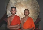 Zwei junge Mönche in orangefarbenem Gewand vor goldenem Gong